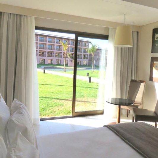 Vista do apartamento com cama de casal e varanda, tudo isso num regime all inclusive ideal para você!